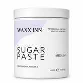A white plastic jar of WAXX INN Sugar Paste in the Medium shade, featuring a minimalist white and light purple label with black text.