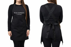 Black apron with 'Wax Experts' branding worn by a person on a white background