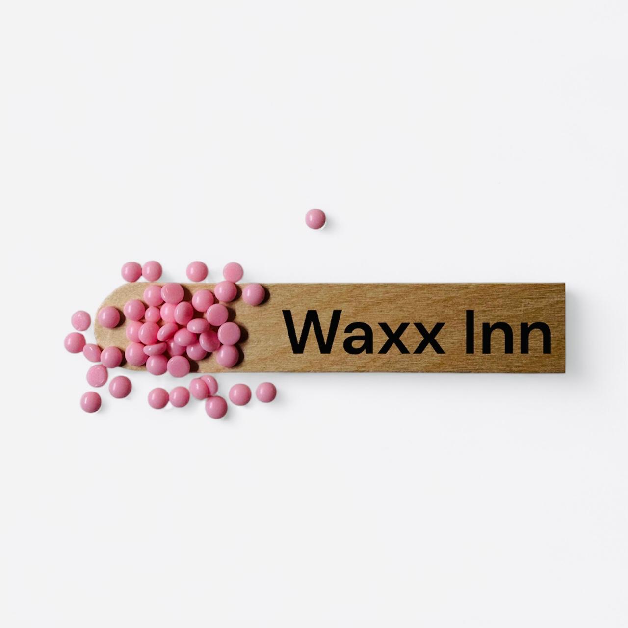 Wooden waxing spatula with pink hard wax beads