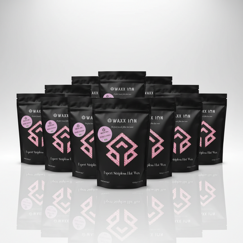 Waxx Inn Pink Candy Expert Stripless Hot Wax Beads 1kg pack of 12 – twelve black pouches with Pink Candy label displayed in a fan arrangement on reflective white surface, bulk professional hard wax made in Italy
